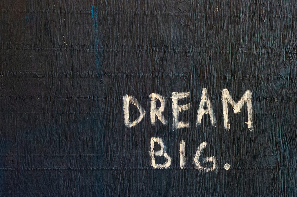 cream text on black background reads "dream big"